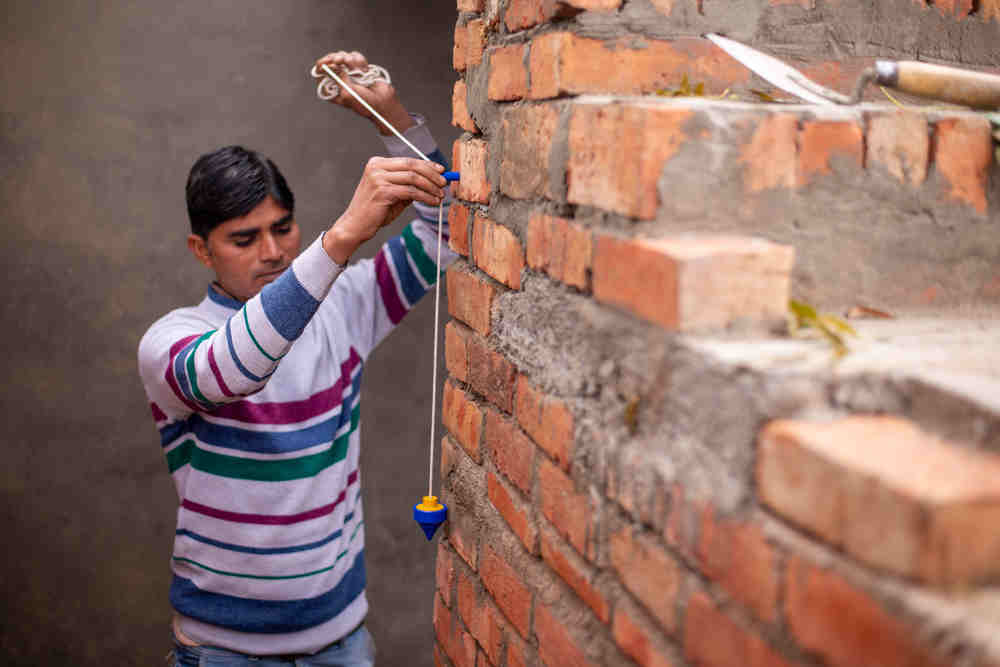 Checking the plumb of wall brick using plumb bob