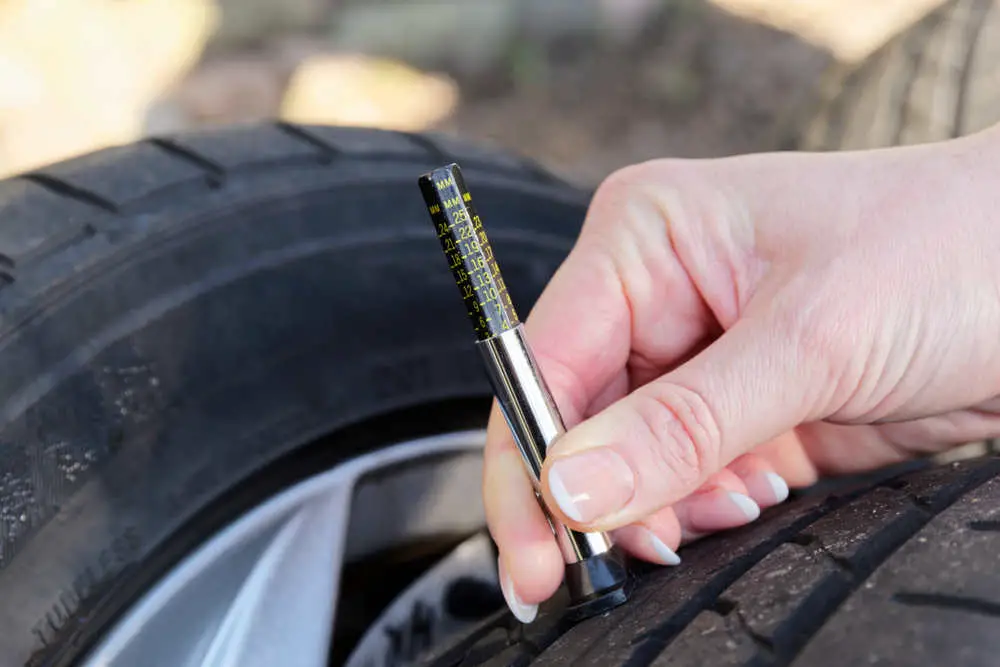 Using tire tread depth gauge to inspect tire condition